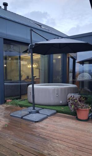 an umbrella sitting next to a bath tub on a deck at Casas De Bouro 2 Casa Dos Jarros in Terras de Bouro