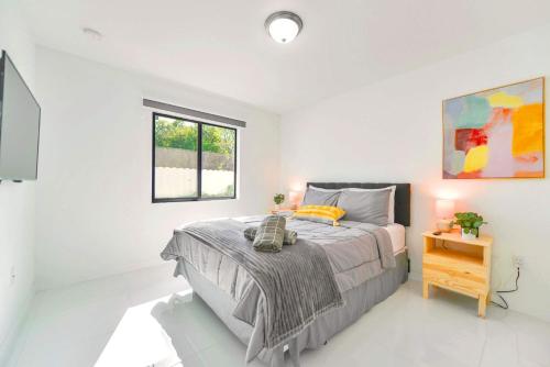 a white bedroom with a bed and a window at Prime Location Duplex with Free Parking in Miami