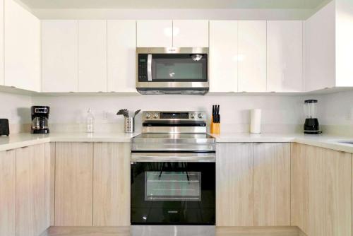 a kitchen with white cabinets and a microwave at Prime Location Duplex with Free Parking in Miami