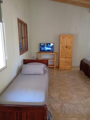 a bedroom with a bed and a dresser with a tv at Tacuarita in Los Hornillos