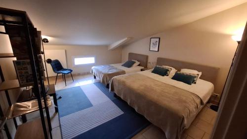 a hotel room with two beds and a chair at Ginette et Marcel la maison in Saint-Rémy-de-Provence