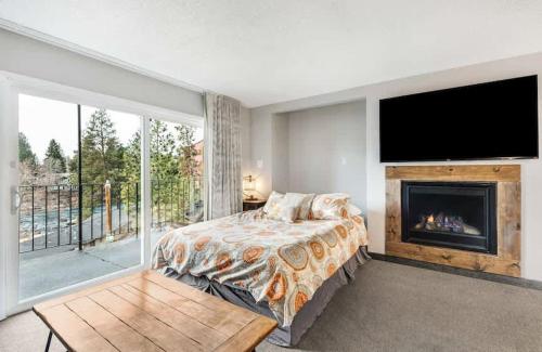 Schlafzimmer mit einem Bett, einem Kamin und einem TV in der Unterkunft River View Condo- Edge of Downtown in Bend