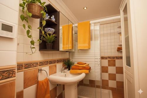 ein Badezimmer mit einem Waschbecken und einer Dusche mit orangefarbenen Handtüchern in der Unterkunft Sierra Nevada Home in Sierra Nevada