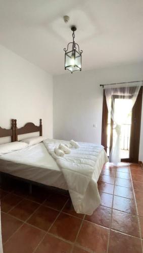 a bedroom with a large white bed with a chandelier at Hotel Restaurante Atalaya in Comares