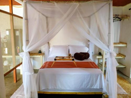 una camera da letto con un letto bianco con baldacchino di Studio Gaya a Palmeiras