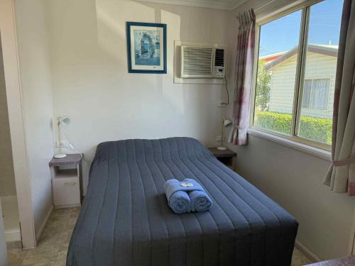 une chambre avec un lit avec une couverture bleue dans l'établissement Maclean Riverside Cabin Park, à Maclean