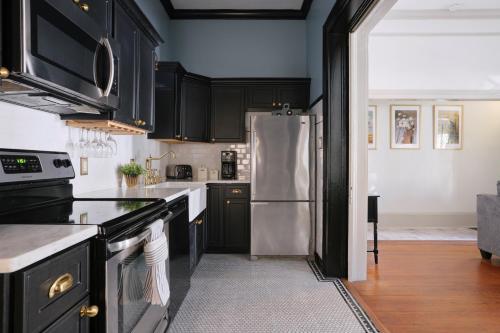 a kitchen with black cabinets and a stainless steel refrigerator at Comfortable Escape in Historic Downtown Savannah in Savannah