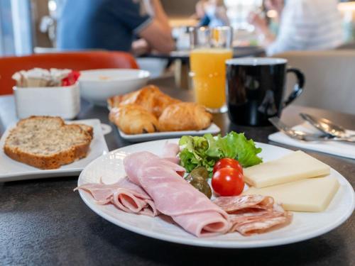a plate of food with meat and cheese and bread at Novotel Deauville Plage in Deauville