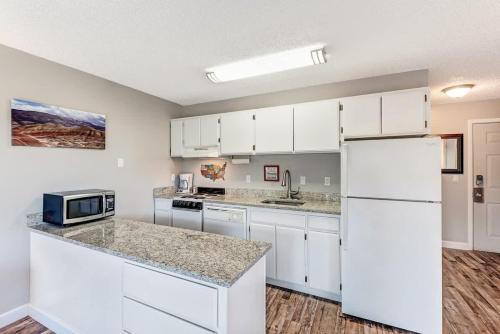 eine Küche mit weißen Schränken und einem weißen Kühlschrank in der Unterkunft Riverfront Condo with Amazing View - Downtown Bend in Bend