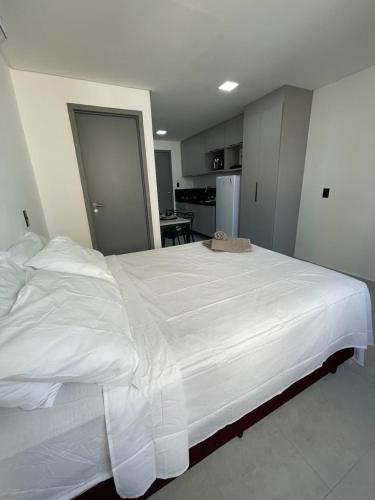 een groot wit bed in een kamer met een keuken bij Flat em Intermares Beach in Cabedelo