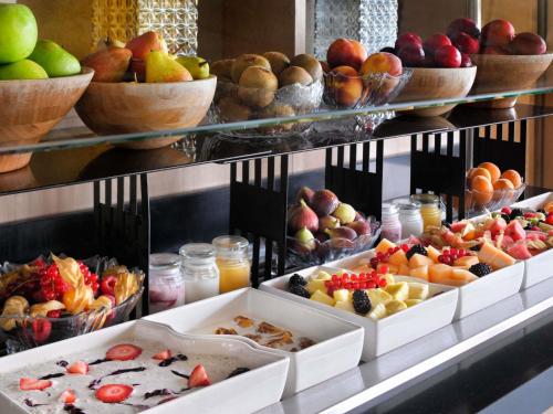 a buffet with bowls of fruit and other food at Mövenpick Hotel Tahlia Jeddah in Jeddah