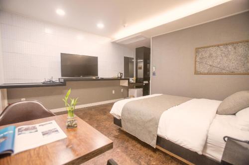 a hotel room with a bed and a desk and a tv at Major Hotel 2 in Jeju