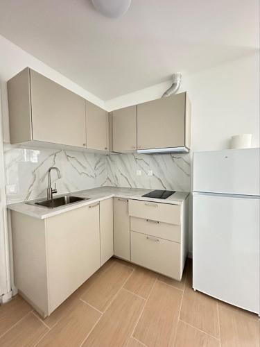 eine weiße Küche mit Spüle und Kühlschrank in der Unterkunft Renovated prestige apartment in Aubervilliers