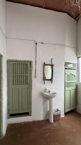 a bathroom with a sink and two green doors at Ankaa Hostel in Flores