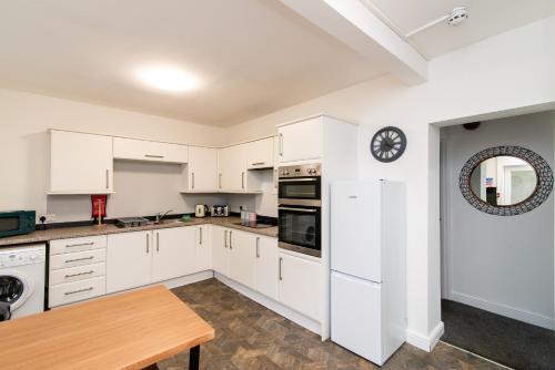 a kitchen with white cabinets and a wooden table at The Linden Leaf Rooms in Nottingham