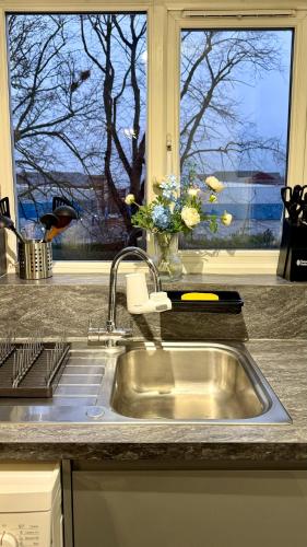 a kitchen sink with a window and a vase of flowers at Modern 2-Bed Flat, Spacious, near Harry Potter Studio in Watford