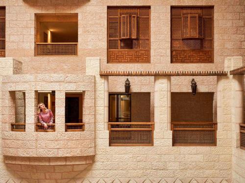 una mujer mirando por la ventana de un edificio en Mövenpick Resort Petra, en Wadi Musa