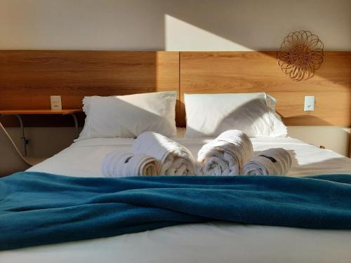 een bed met een stapel opgevouwen tijdschriften erop bij Quarto e banheiro privativo pet friendly in Garopaba