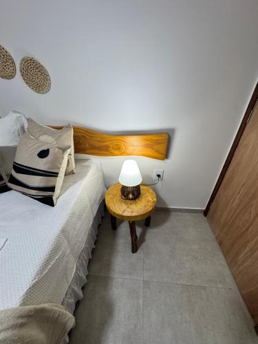 een slaapkamer met een bed en een tafel met een lamp bij Pousada Vila Mar Japaratinga in Japaratinga