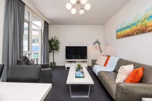 a living room with a couch and a tv at 1 Bdrm With Parking, Walk to Beach in Melbourne