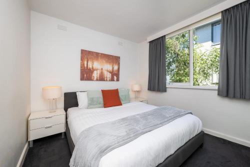 a white bedroom with a large bed and two windows at 1 Bdrm With Parking, Walk to Beach in Melbourne