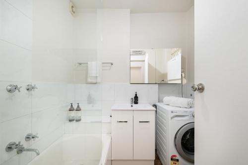 a white bathroom with a washing machine and a washer at 1 Bdrm With Parking, Walk to Beach in Melbourne