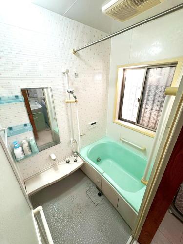 a bathroom with a blue tub and a mirror at Nikko Central GOKO STAY in Nikko