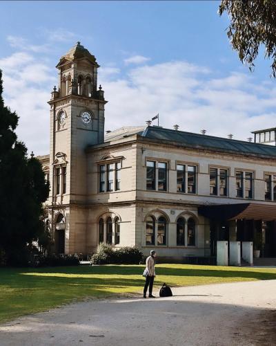 a man standing in front of a building with a clock tower at Lancemore Mansion Hotel Werribee Park in Werribee