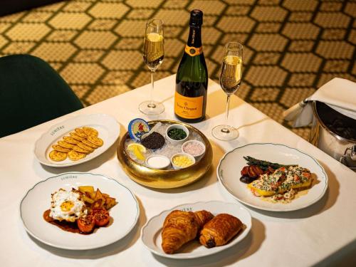 una mesa con platos de comida y copas de vino en Fairmont Century Plaza Los Angeles at Beverly Hills, en Los Ángeles
