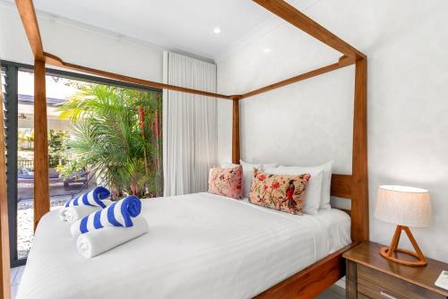 a bedroom with a large white bed with a window at Belle Escapes Castaways in Palm Cove