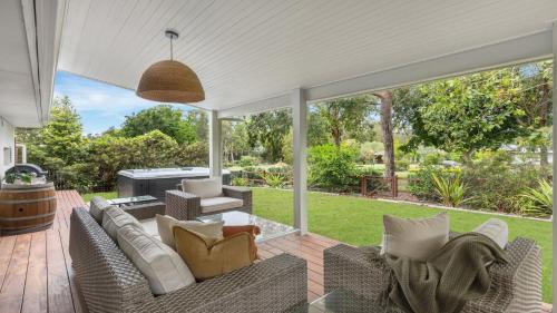 een patio met een bank en stoelen bij Holiday Retreat in Pokolbin