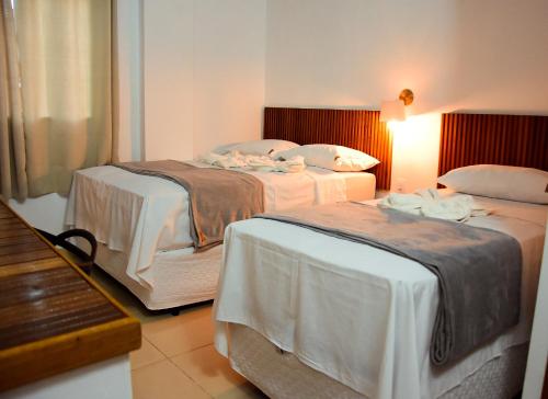 two beds in a hotel room with a bench at Hotel Ipe in Barreirinhas