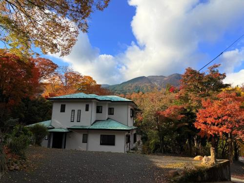 a white house with a green roof in the woods at 箱根宿燕帰 in Hakone