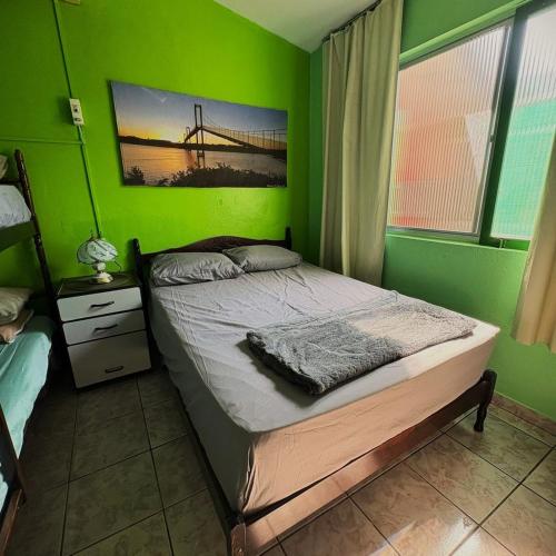 ein grünes Schlafzimmer mit einem Bett und einer Brücke in der Unterkunft Casa Ver-de-perto o Mar in Barra Velha