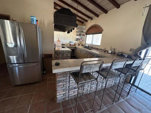 una cucina con frigorifero e bancone con sedie di Wine Hotel Punta Arena a Bahía de los Ángeles