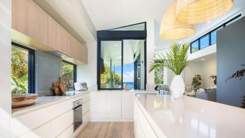 a kitchen with white cabinets and a large window at Luxury On The Bay - Wanda in Suffolk Park