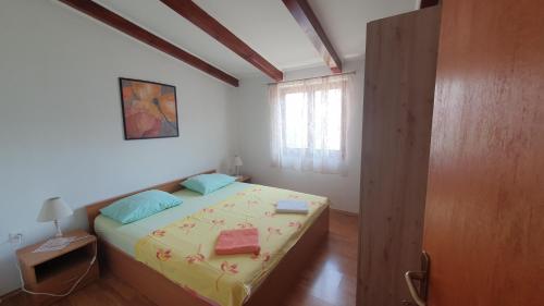 een slaapkamer met een bed met twee kussens en een raam bij Apartment Cunski 7951a in Čunski