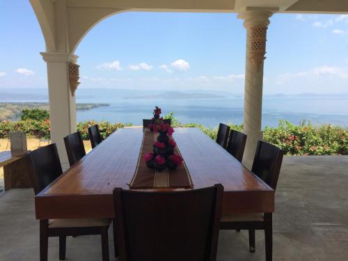 a long wooden table with chairs and a view of the ocean at Ataalaya Farmhouse in Batangas City