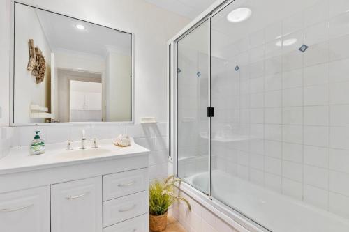 a white bathroom with a shower and a sink at Rainbow Tides - Rainbow Beach in Rainbow Beach