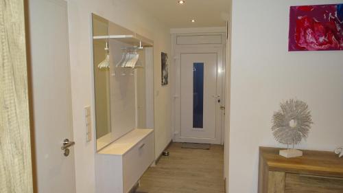 un corridoio con un bagno con lavandino e specchio di Ferienhaus Plattfisch a Dornum