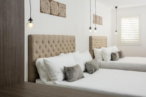 a bedroom with two beds with white and gray pillows at Newington Apartments in Ballarat