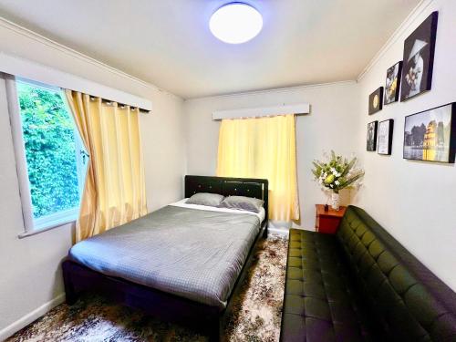 a bedroom with a bed and a couch and a window at Entire House in Mt Wellington, Central Auckland in Auckland