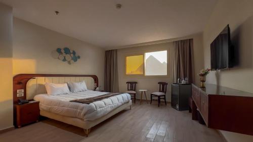een slaapkamer met een bed en een flatscreen-tv bij Pyramids View Hotel in Caïro