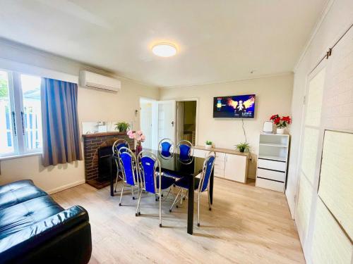 a living room with a dining room table and blue chairs at Entire House in Mt Wellington, Central Auckland in Auckland