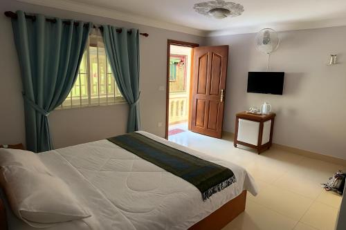 a bedroom with a bed and a window and a television at La Villa 23 Signature in Siem Reap