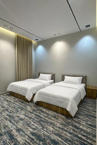 due letti in una stanza con pareti bianche e moquette di بيتك الثاني a Abha