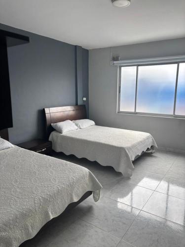 a bedroom with two beds and a window at Hotel Madeira in Manizales
