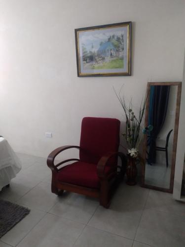 einen roten Stuhl in einem Raum mit einem Bild an der Wand in der Unterkunft C'VAR Community Vacation Apartment Rentals in Saint Michael