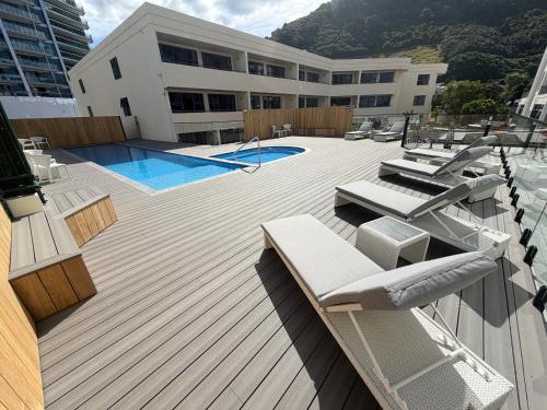 a deck with chairs and a swimming pool on a building at Oceanside Apartment in Mount Maunganui