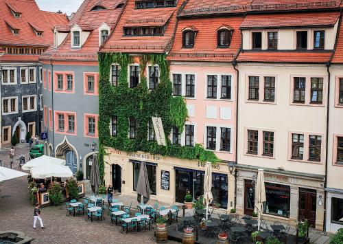 uma rua da cidade com mesas, cadeiras e edifícios em Pirnscher Hof - Hotel Garni em Pirna